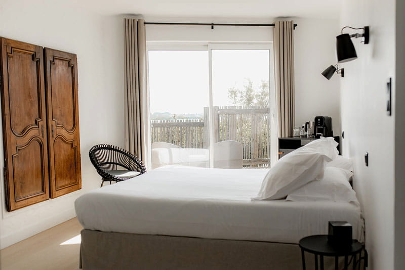 SUPERIEURE-web Lit double avec des draps blancs, au milieu de la chambre.